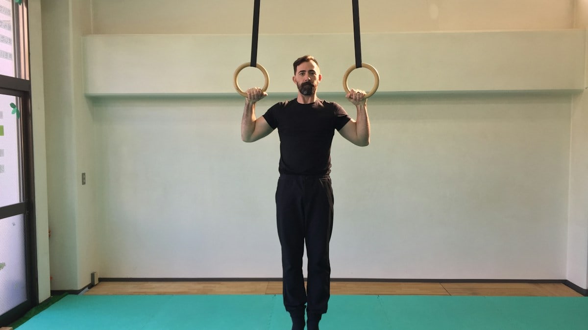 man doing pull-ups on gymnastic rings